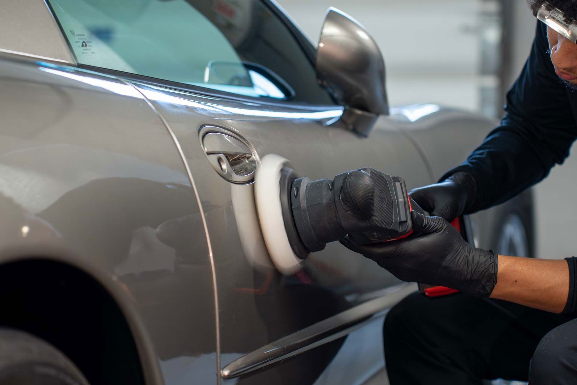 A man is polishing a car with a polisher.