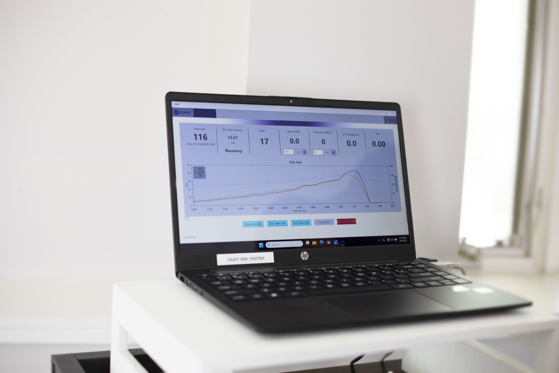 Black laptop displaying a graph, on a white shelf. Window in the background.