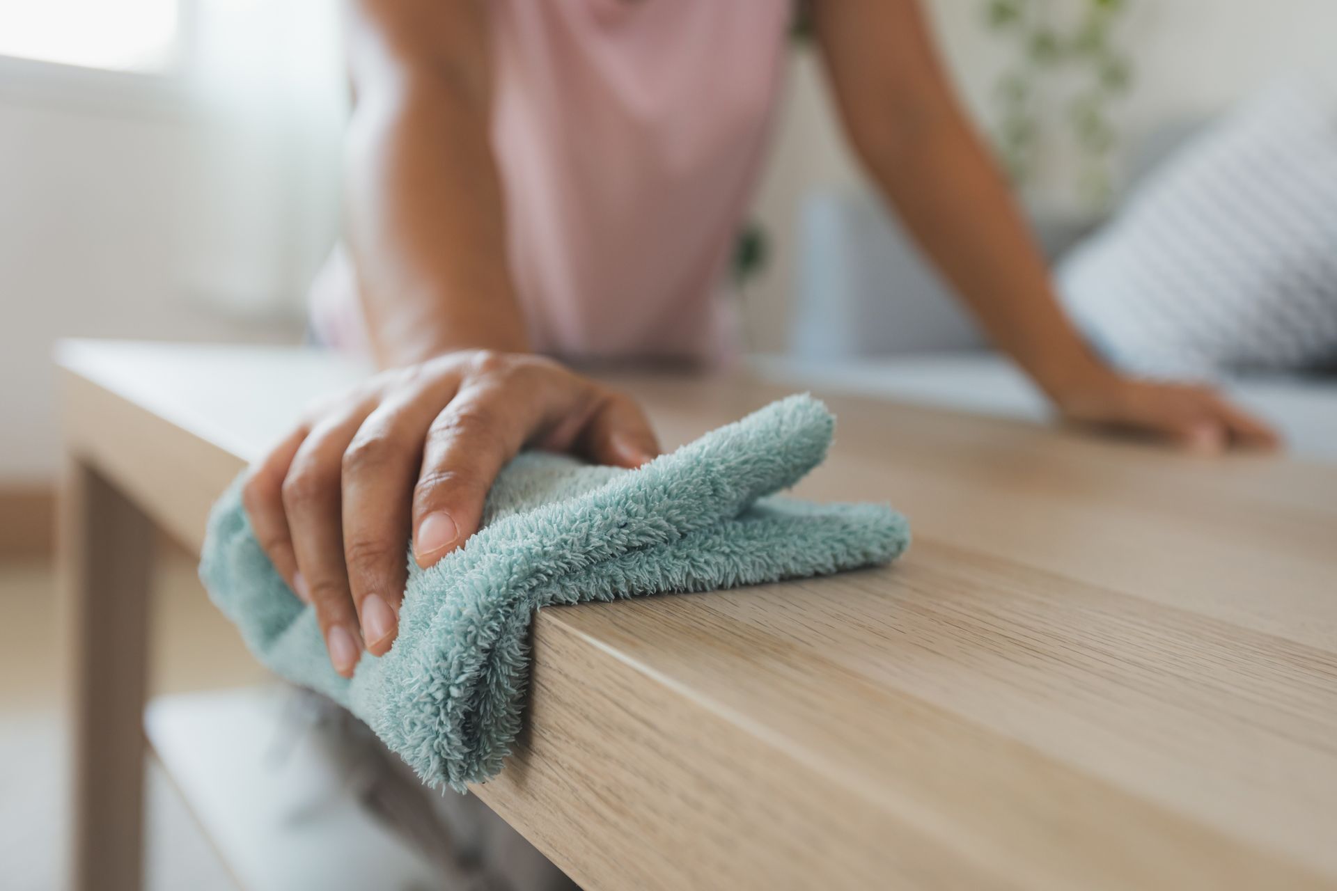 a woman is cleaning a wooden table with a cloth .