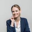 A woman in a blue jacket and white shirt is smiling