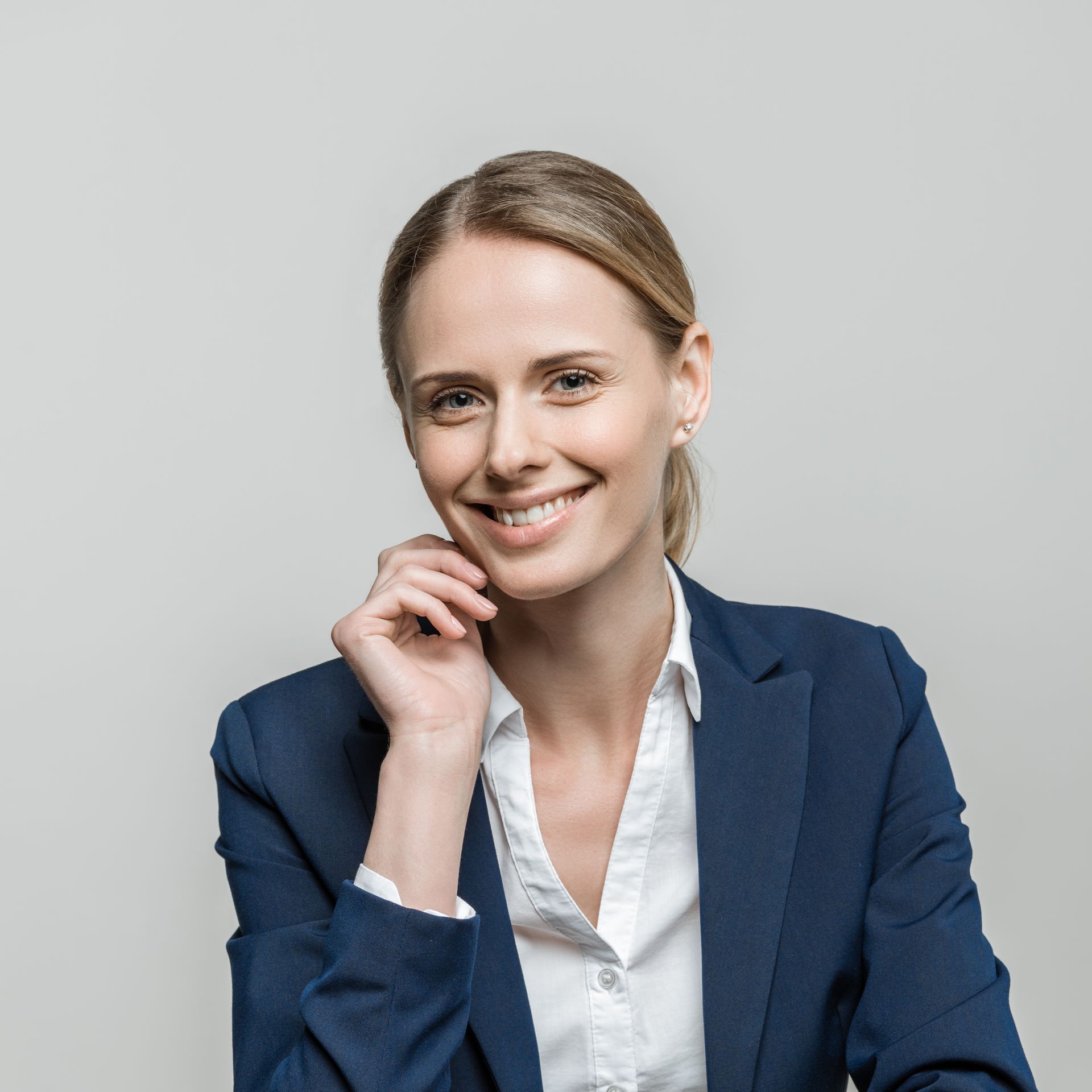 A woman in a blue jacket and white shirt is smiling