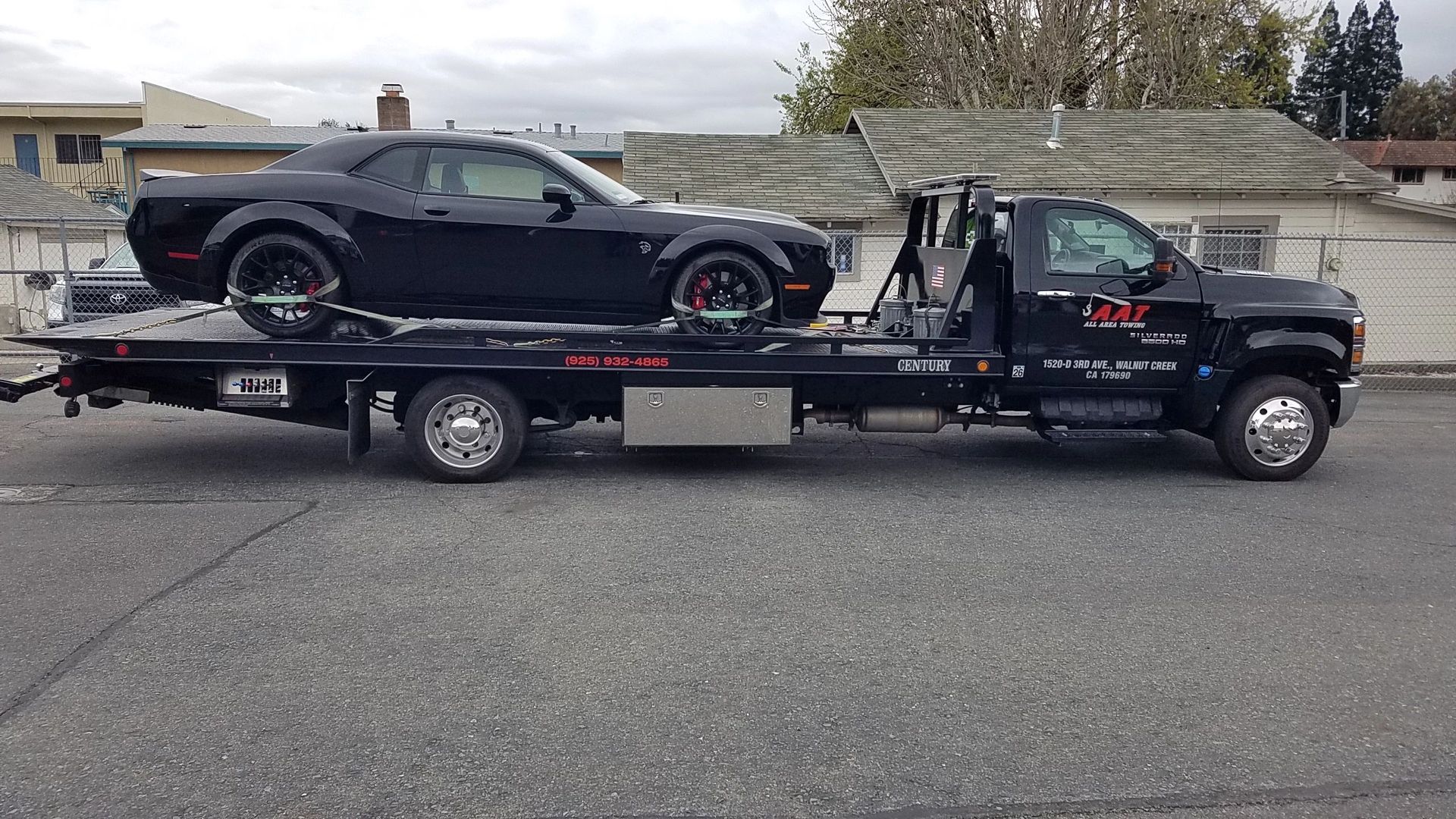 A man is towing a car on a tow truck.
