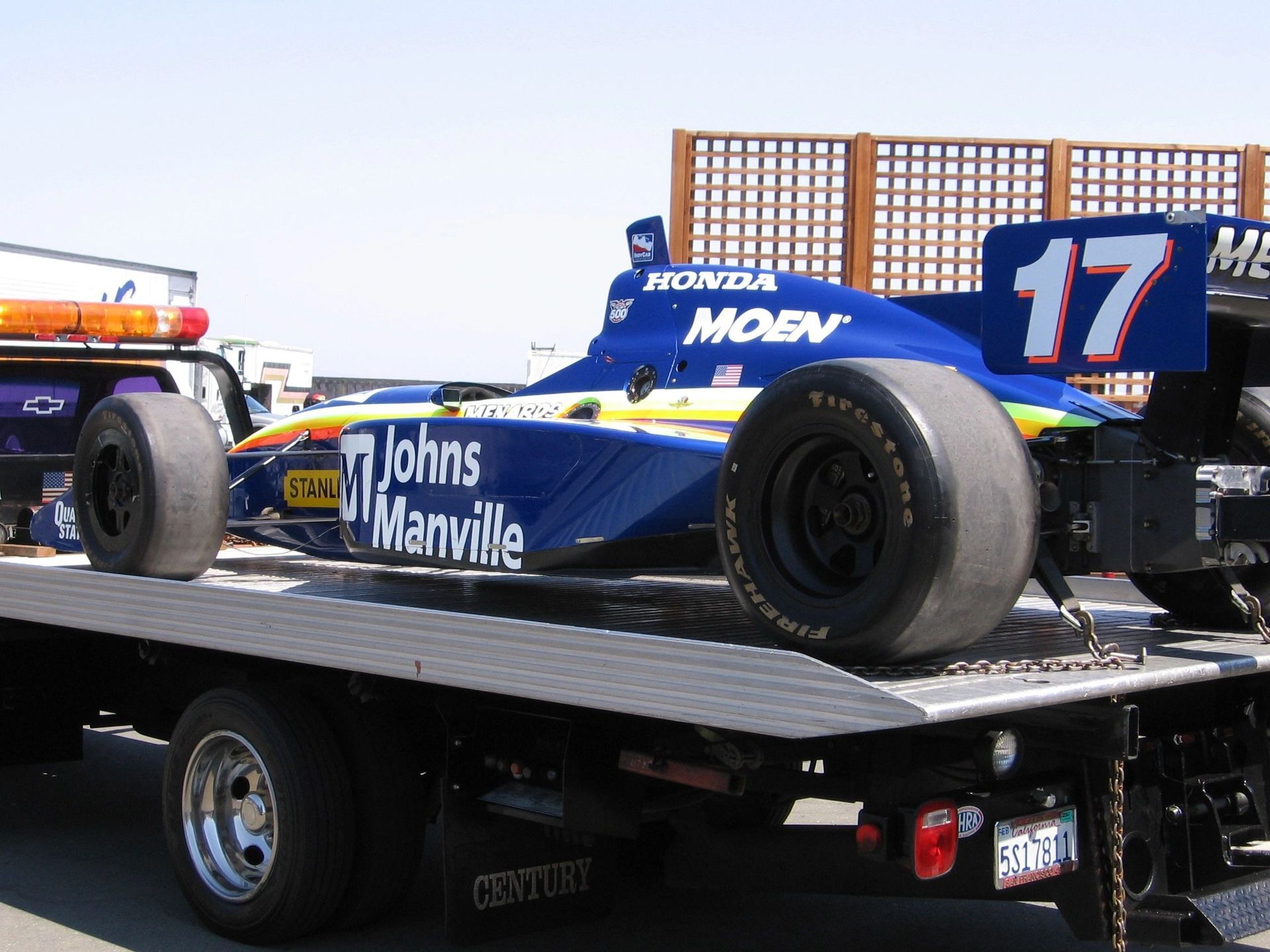 A silver car is being towed by a blue tow truck.
