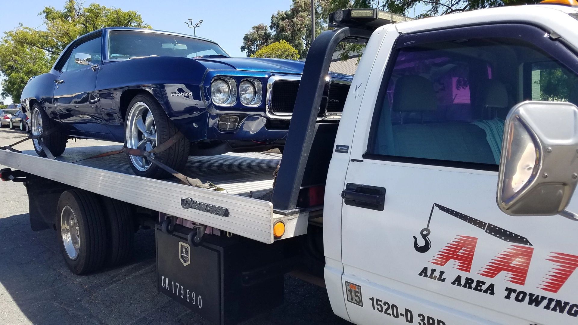 A white car is being towed by a red tow truck.