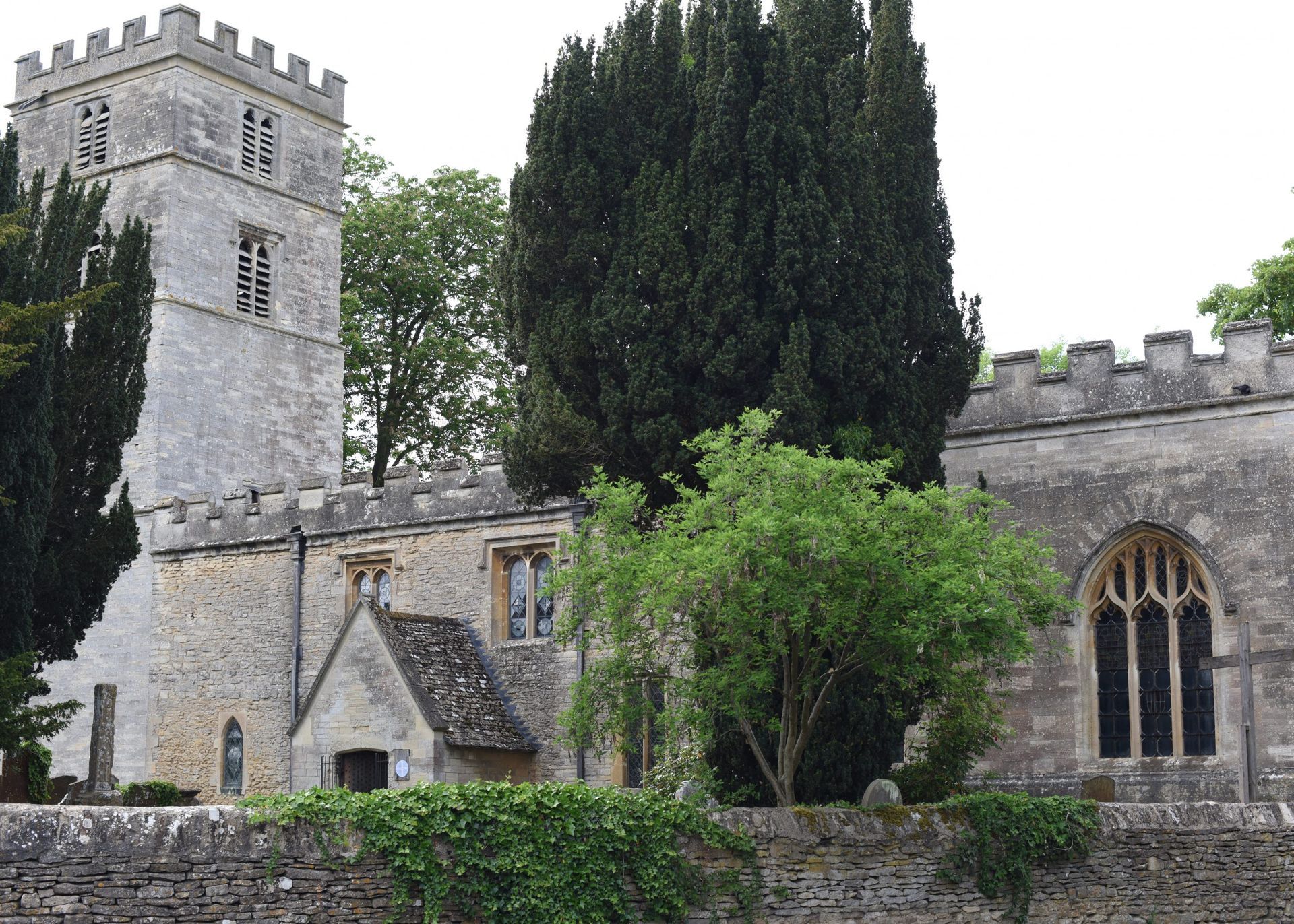 A large stone church in Yarnton with a tower and trees in front of it called St Bartholomew's Church