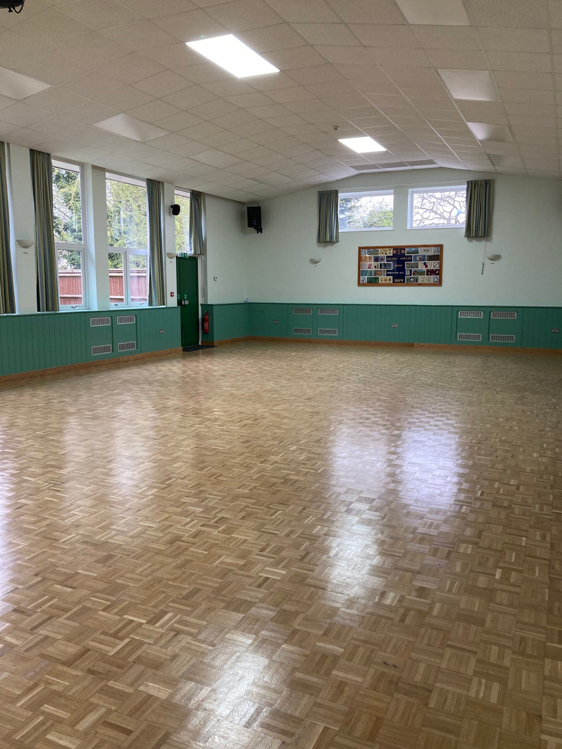 A large empty room with a wooden floor and green walls.