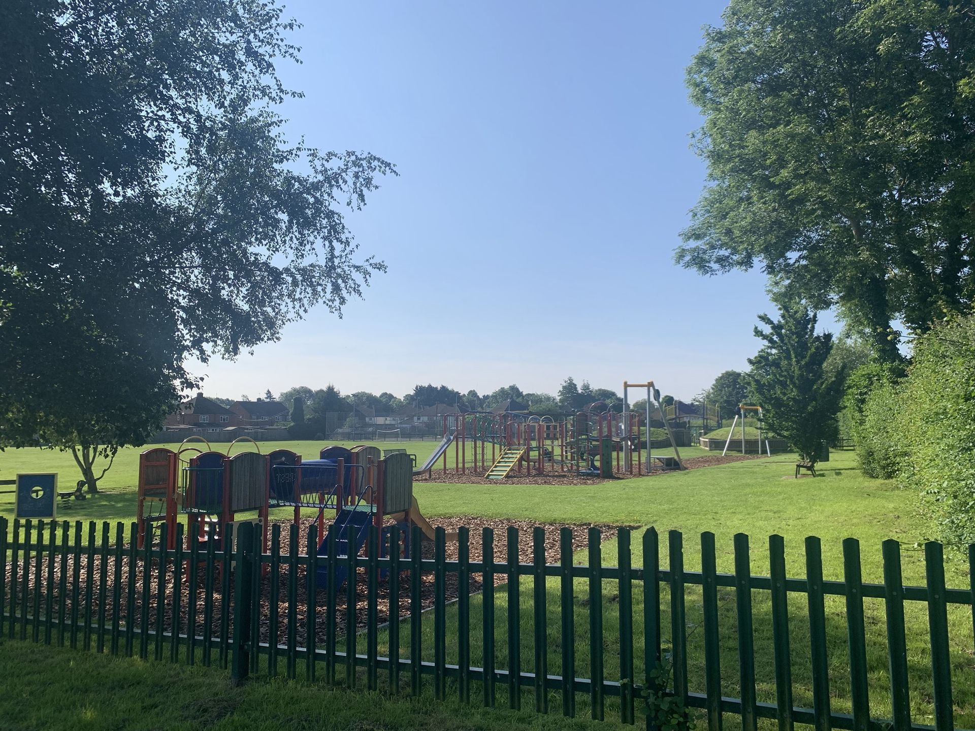 A playground is behind a fence in a park