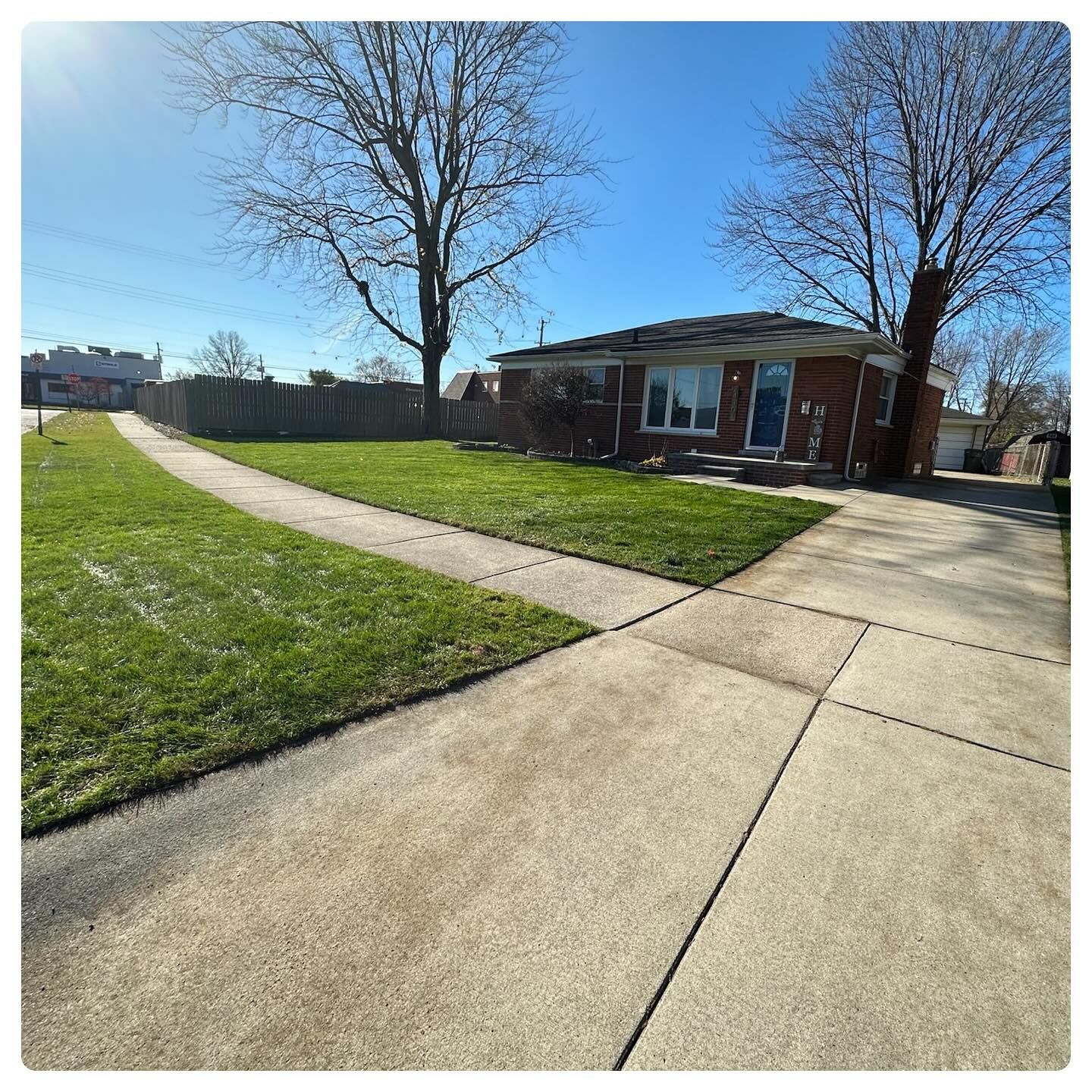 Suburban house with brick facade, curved driveway, and leafless trees on a sunny day