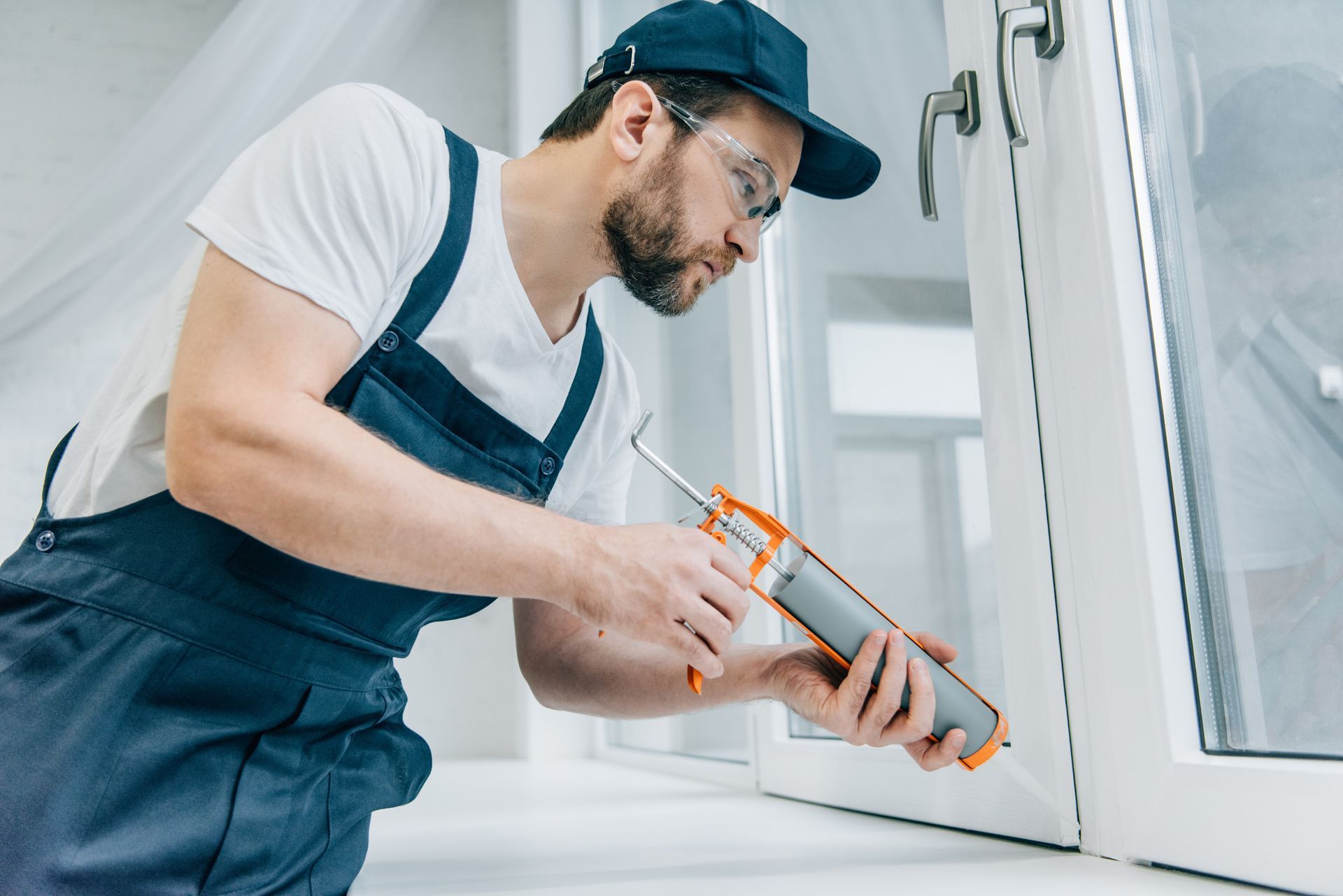 Technician applying caulk or sealant around a residential window frame.