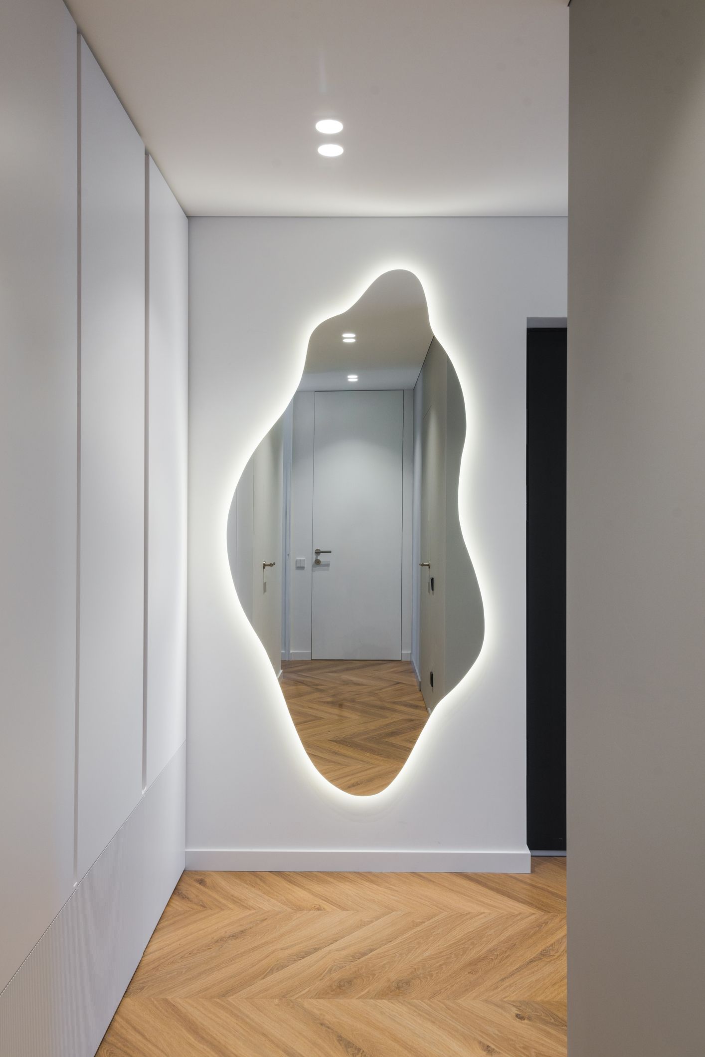 Stylish backlit mirror in apartment corridor by closet. Stylish backlit mirror in apartment corridor by closet.