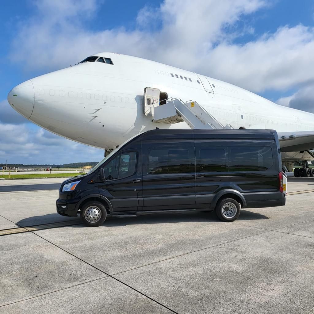 A black van is parked in front of a large white airplane.