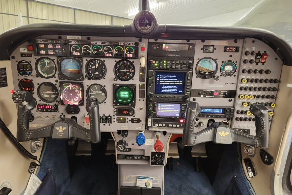 Compact airplane cockpit with analog gauges, digital displays, and control switches