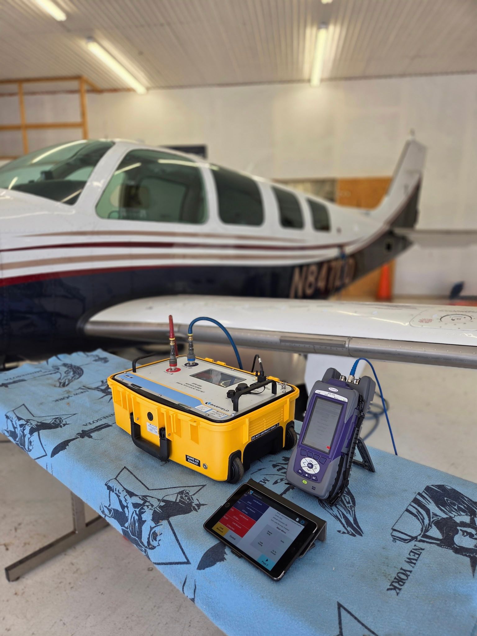 Mechanics working under a small airplane in a hangar, with the propeller and landing gear visible