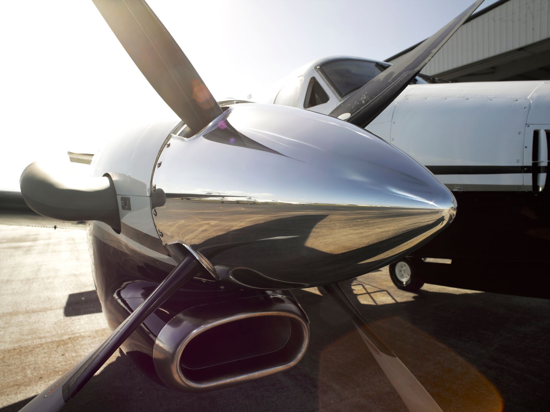 Small white airplane in a hangar with maintenance tools and equipment nearby