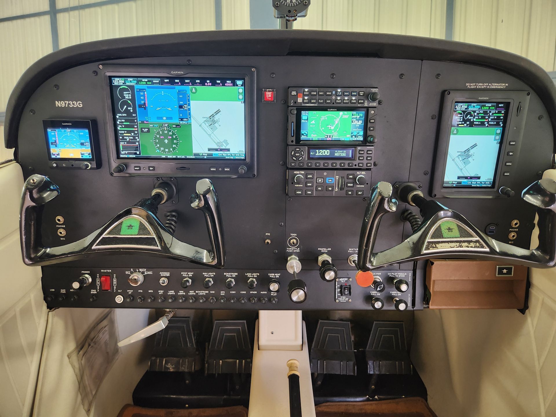 Airplane cockpit with multiple flight displays, control yokes, and instrument panels in a compact cabin