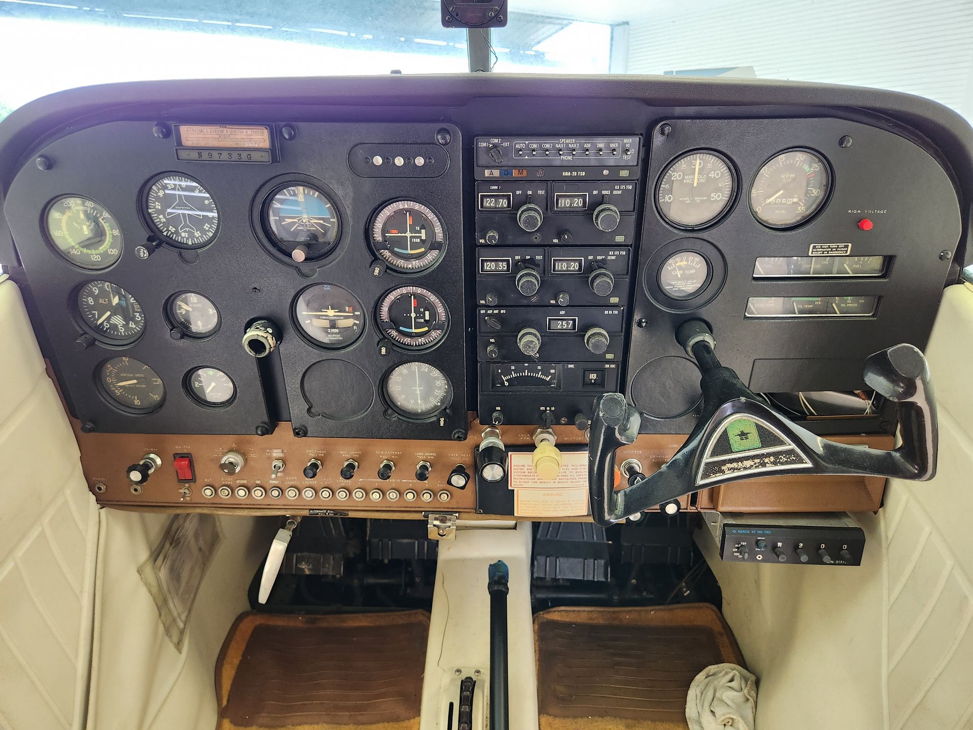 Airplane cockpit panel with analog gauges, switches, and a central control column