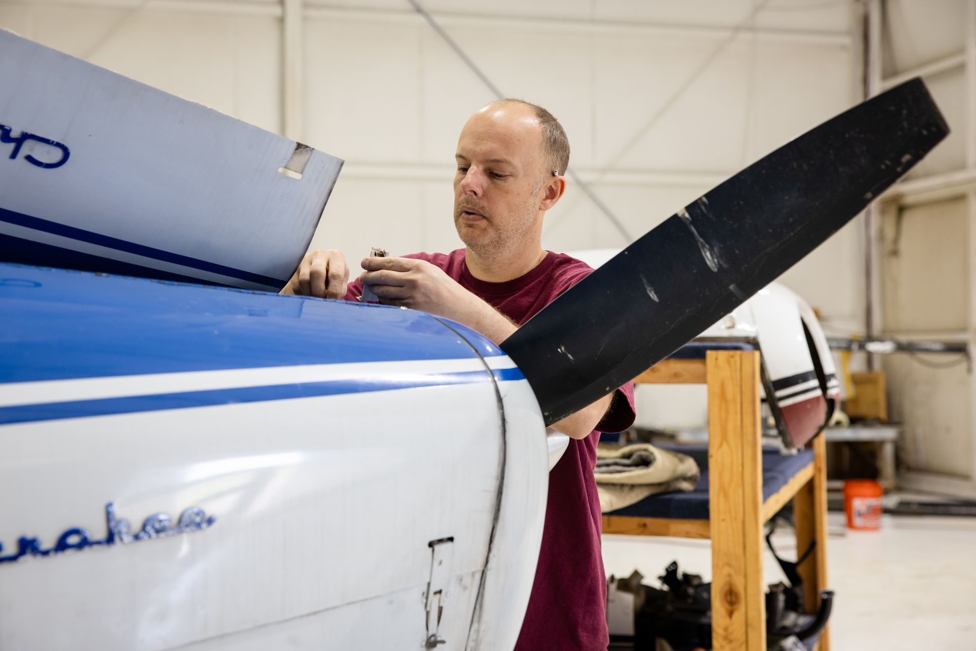Man working on a white aircraft wing in a hangar