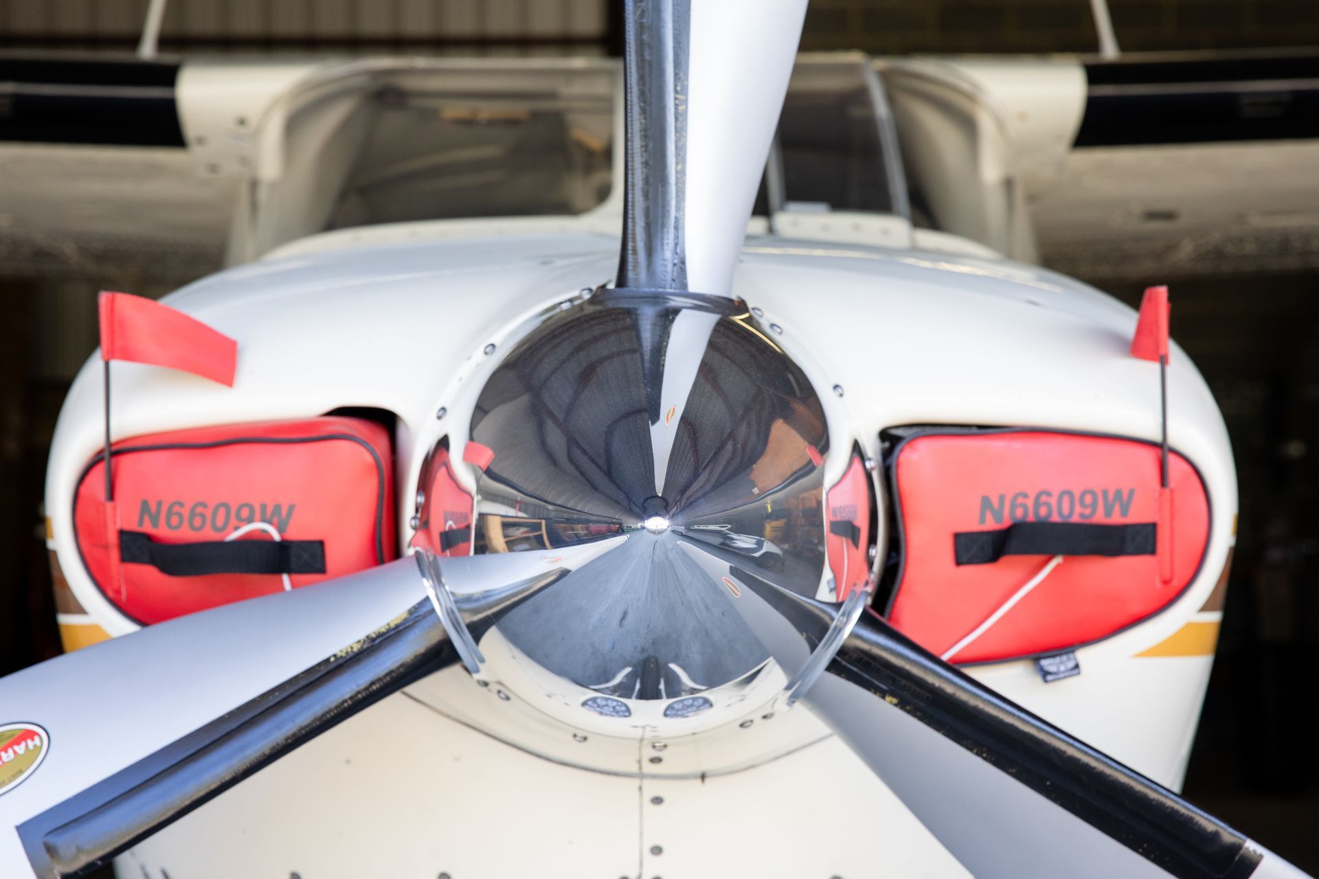 Front view of a small white airplane with red-covered engine intakes and propeller blades