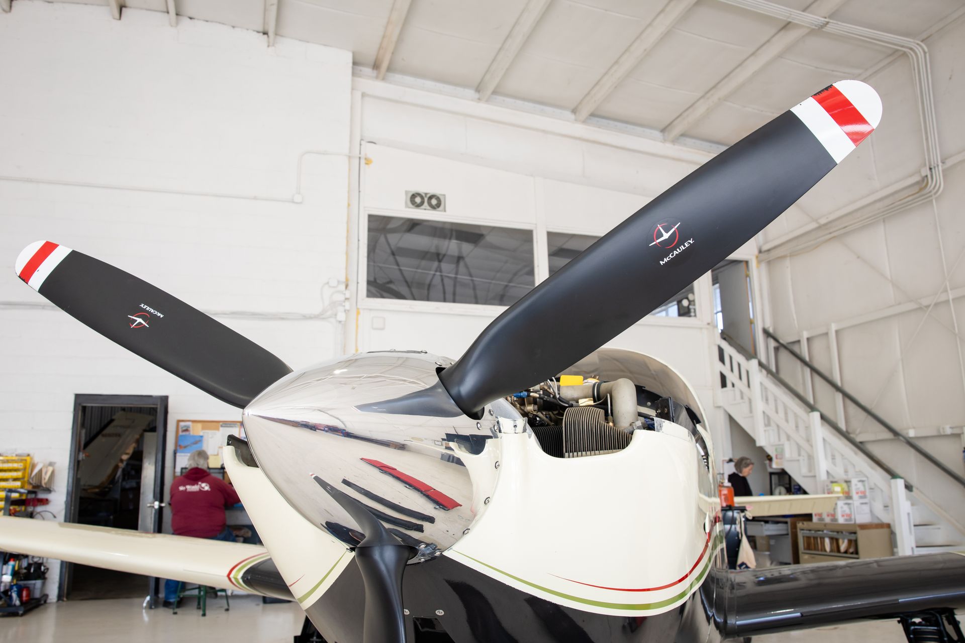 Single-engine airplane in a hangar, close-up of the nose and propeller.