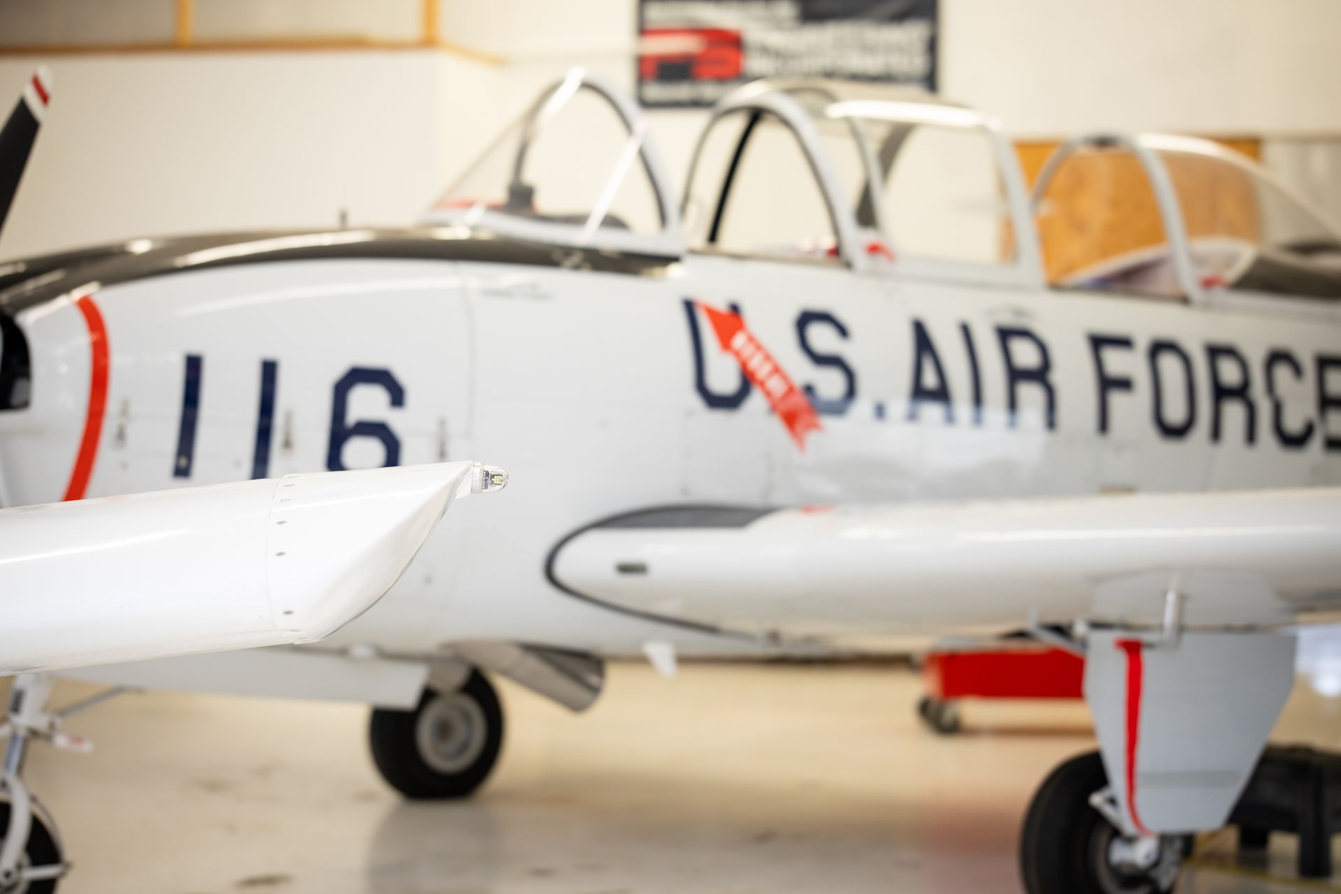 White U.S. Air Force jet in a hangar, with red trim and cockpit canopy visible