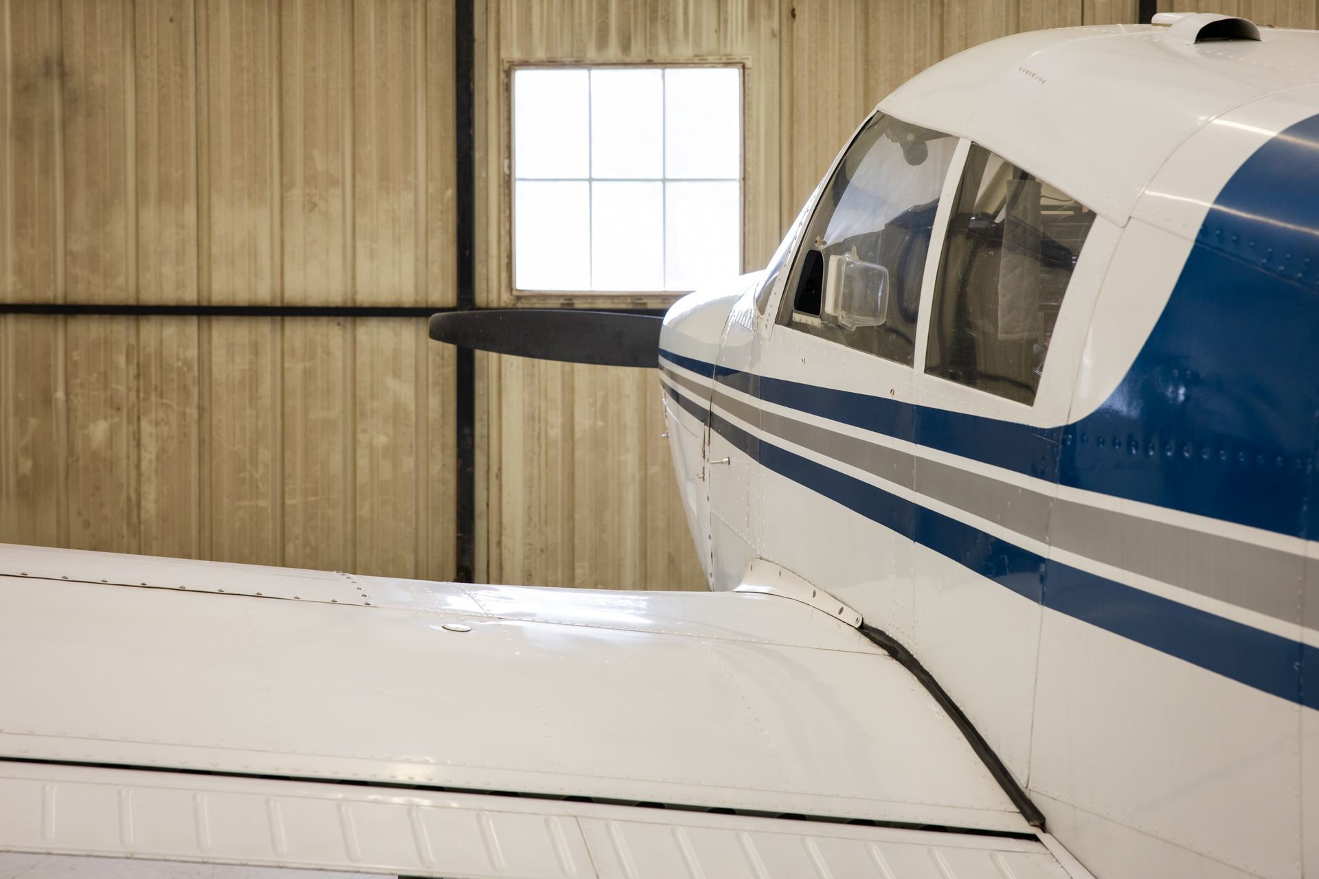 White and blue small airplane parked inside a hangar