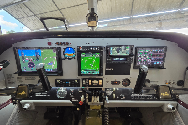 Cockpit with multiple digital flight displays, control yokes, and instrument panels inside a small aircraft