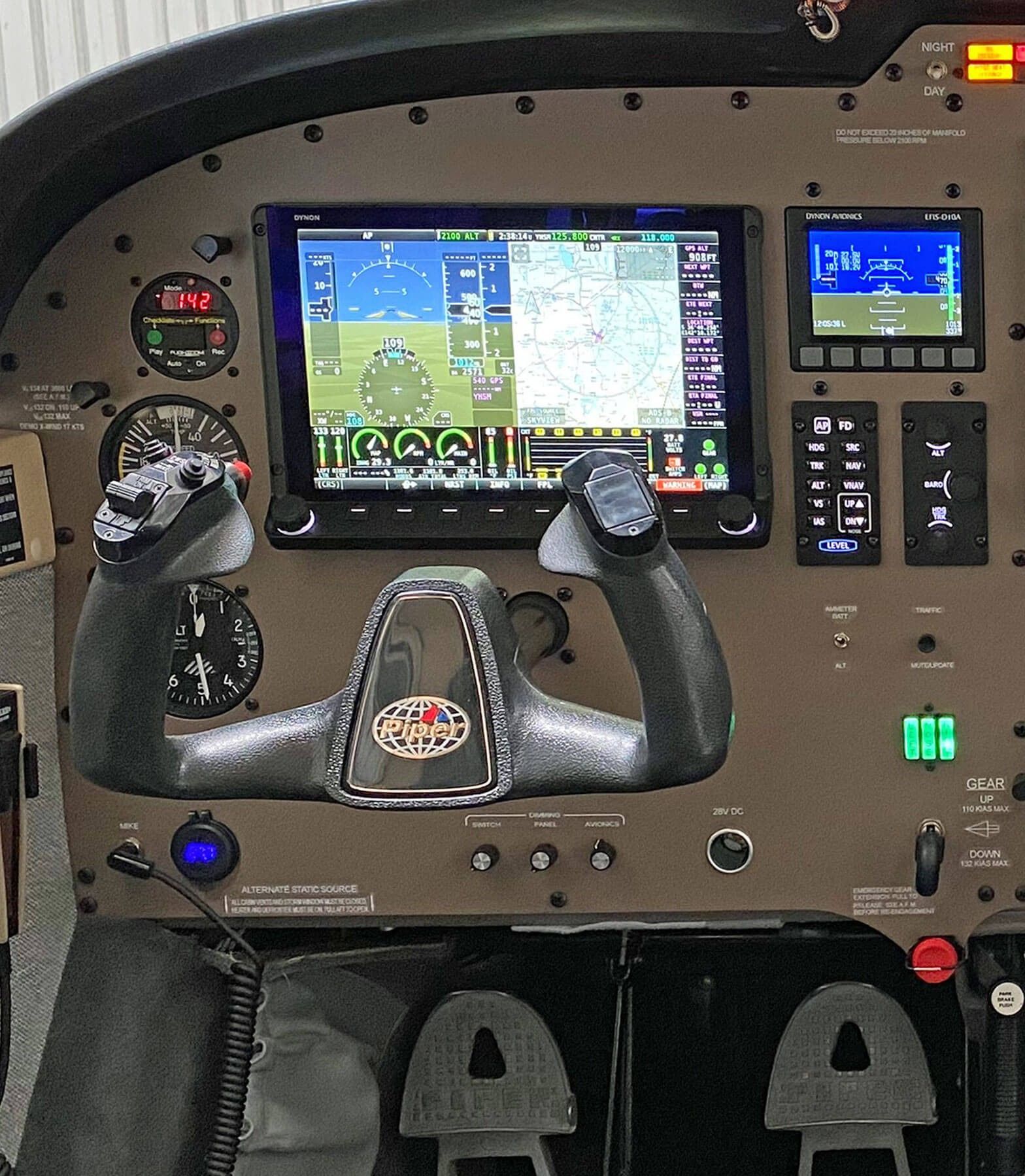 Cockpit panel with flight display, control yokes, and gauges inside a small aircraft