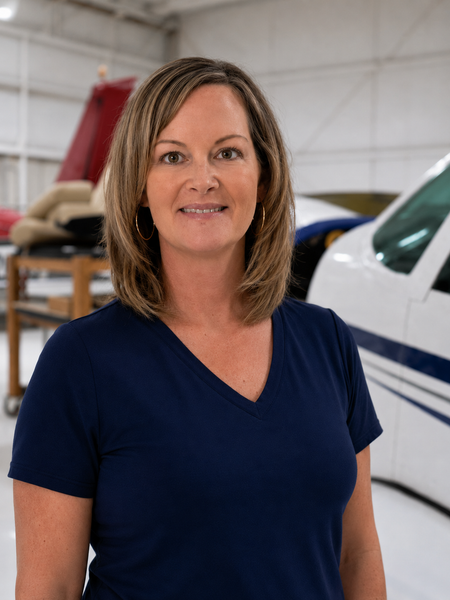 Woman in a navy shirt standing in a hangar beside a white airplane