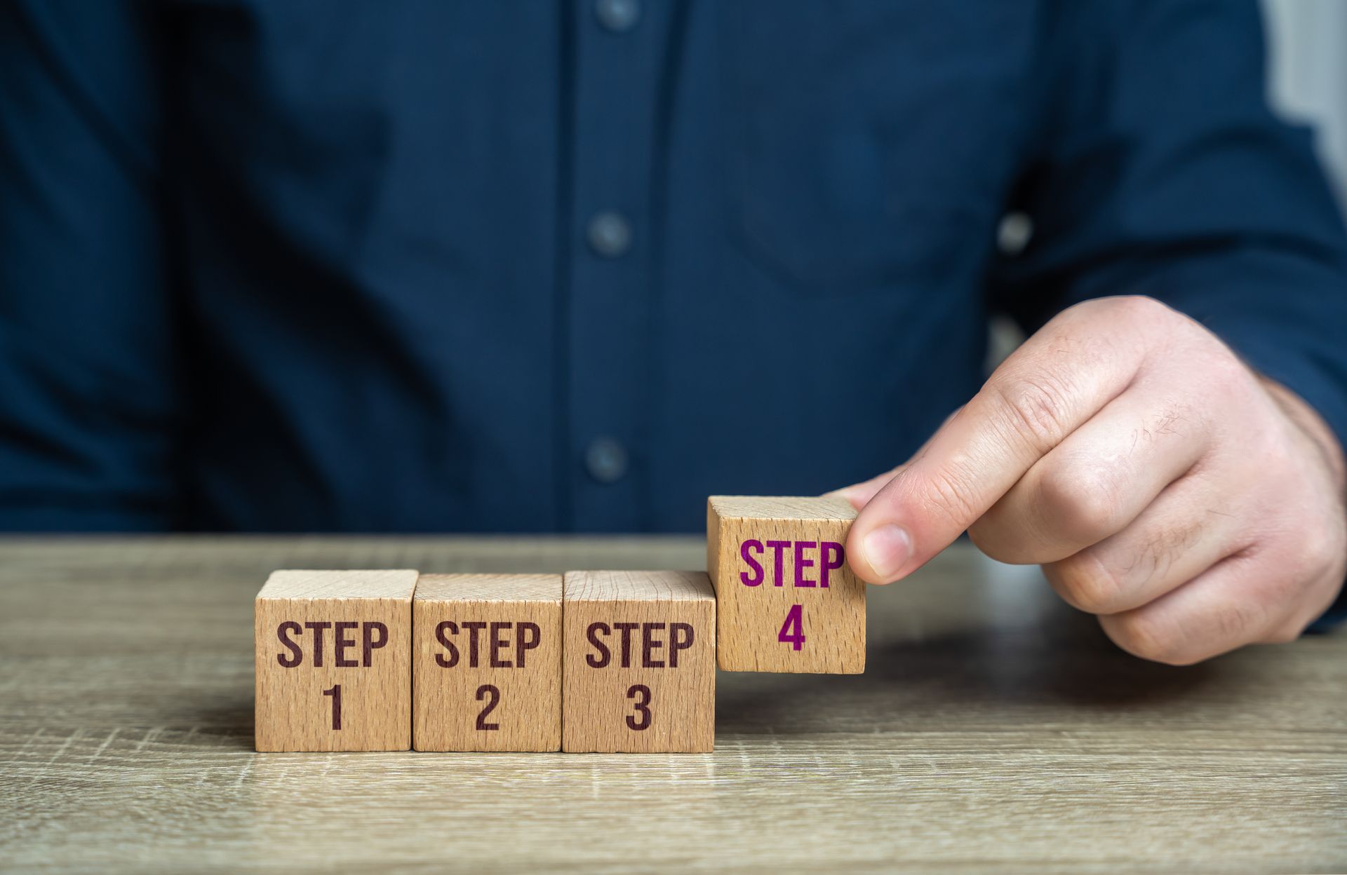 A man is holding a wooden block with the word step on it.