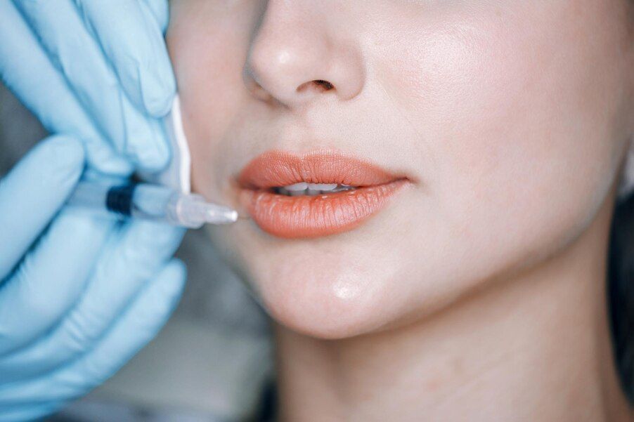 A woman is getting a botox injection in her lips.