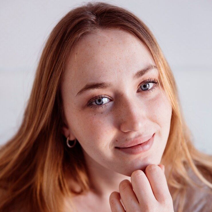 A close up of a woman 's face with her hand on her chin