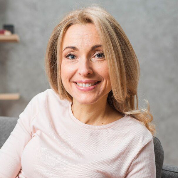 A woman is smiling while sitting on a couch.