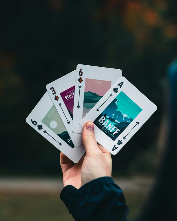 Hand holding four playing cards fanned out against a blurred outdoor background