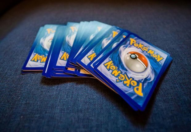 A fan of blue Pokémon trading cards spread on dark fabric