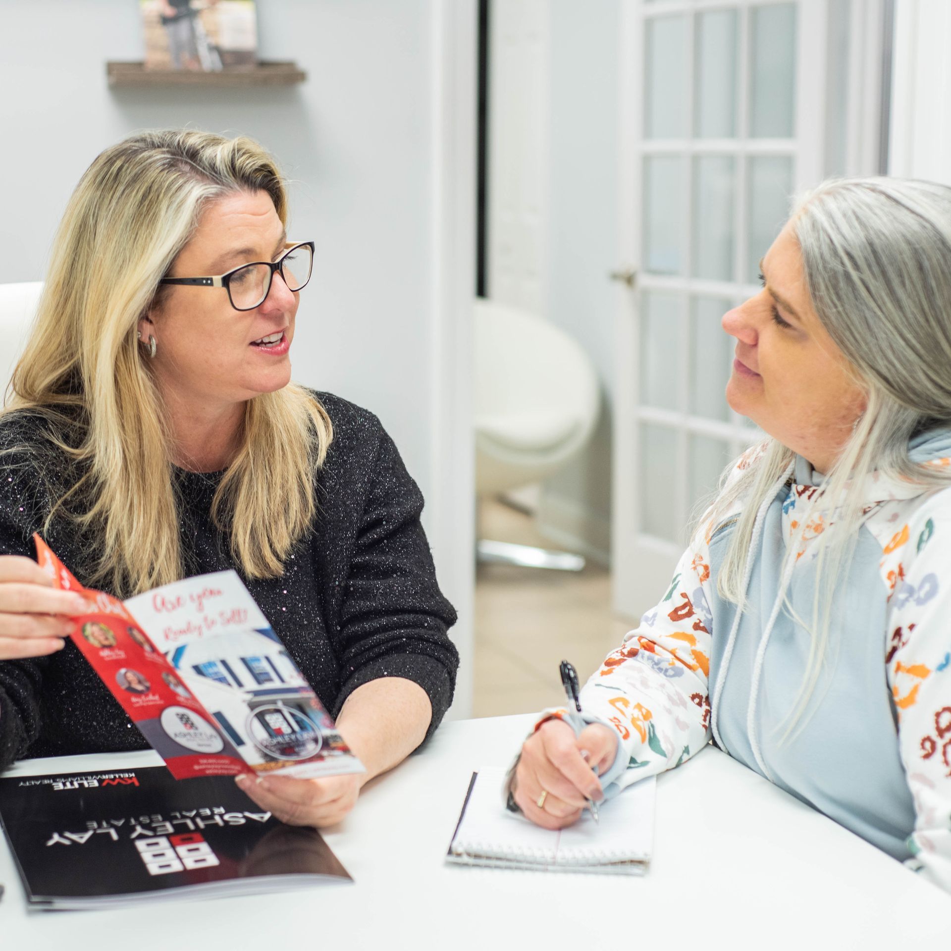 Two Ashley Lay Real Estate team members in conversation at the office