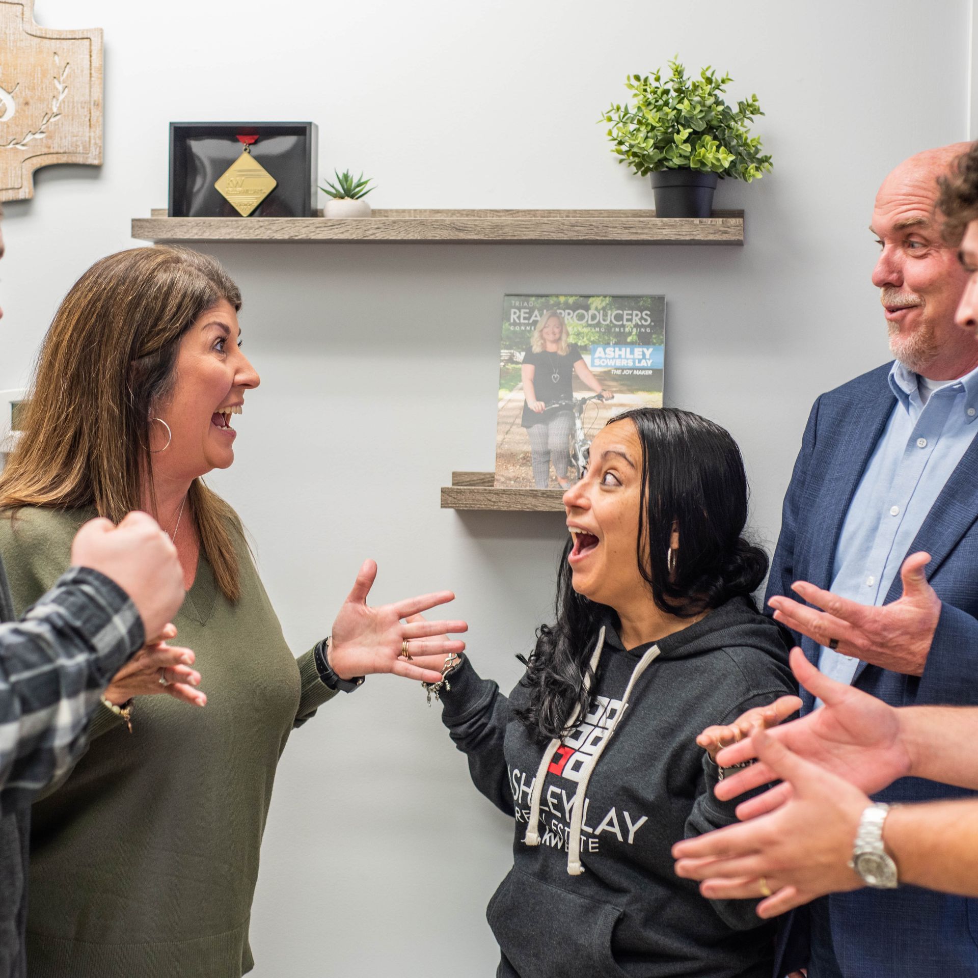 Ashley Lay Real Estate team members reacting with excitement during a team meeting