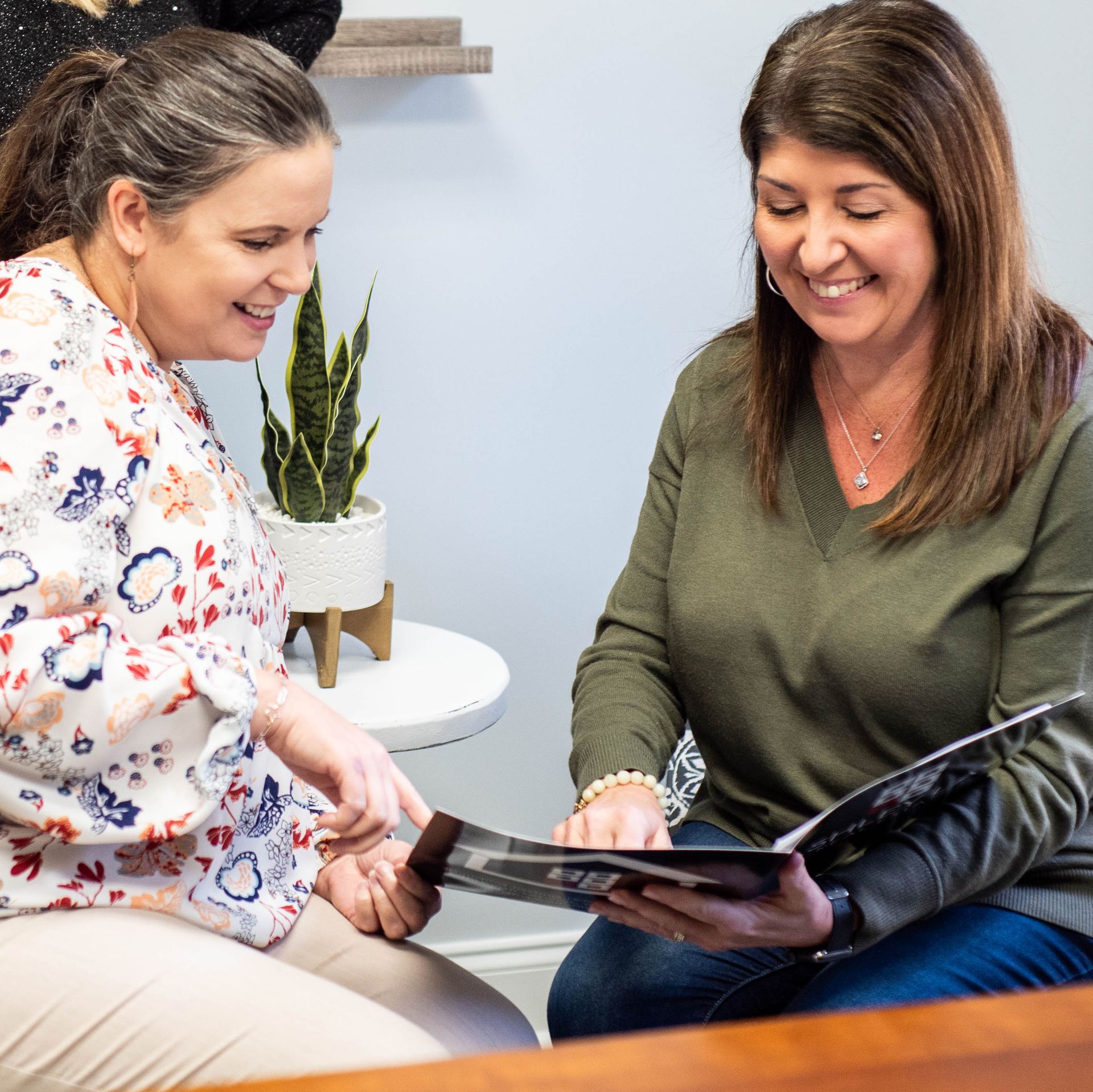 Two Ashley Lay Real Estate team members laughing together during a meeting