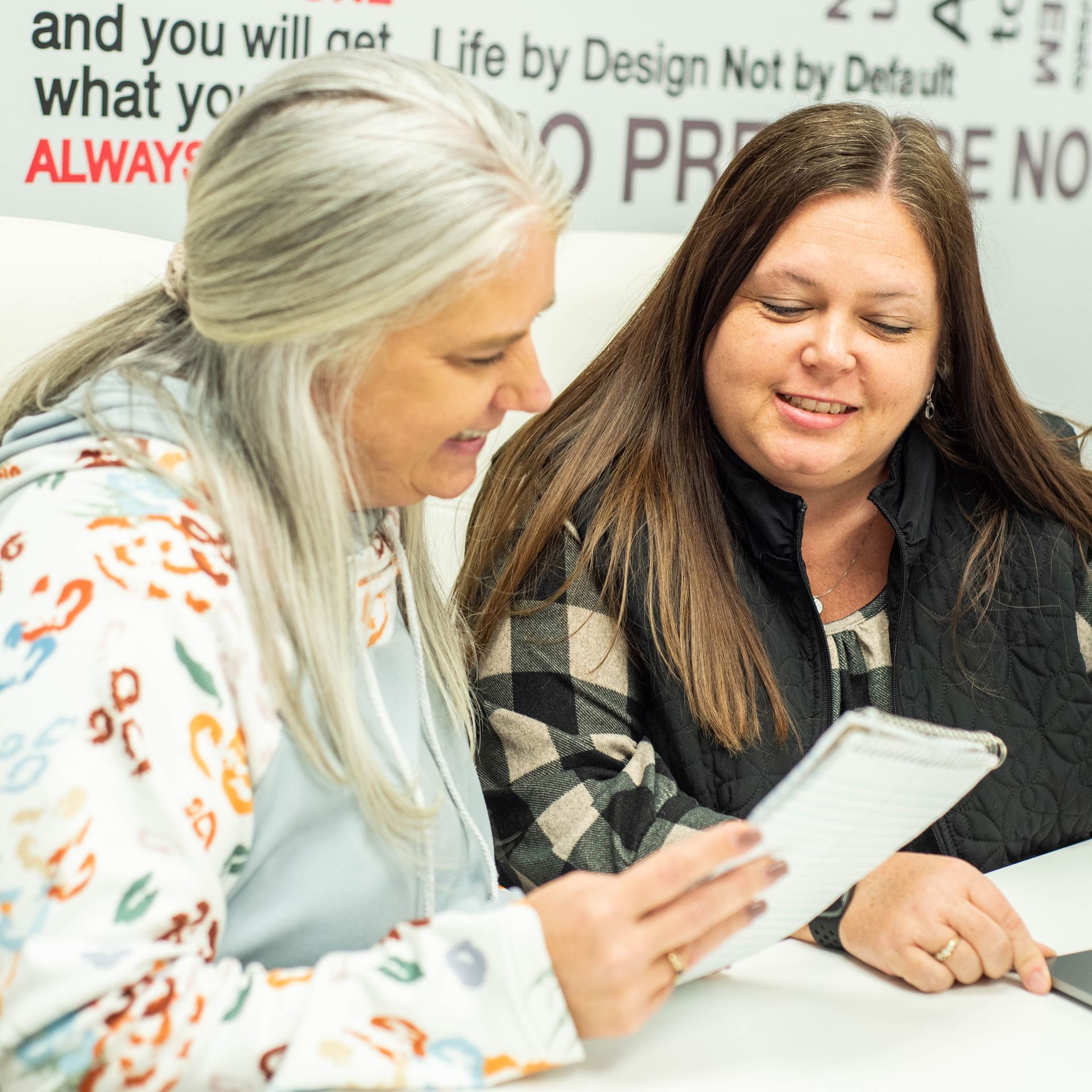 Two Ashley Lay Real Estate team members reviewing motivational signage at the office