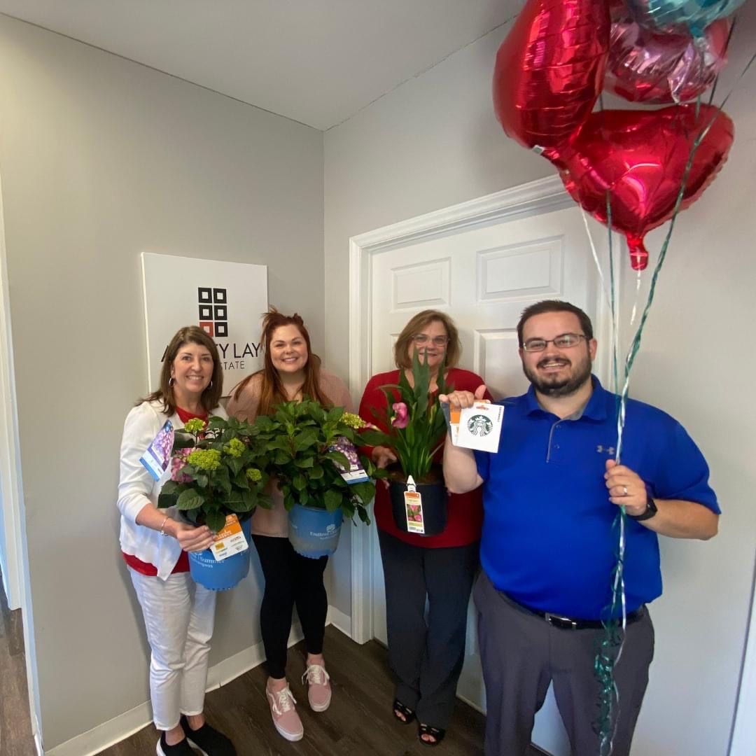 Ashley Lay Real Estate team members celebrating with balloons in the office