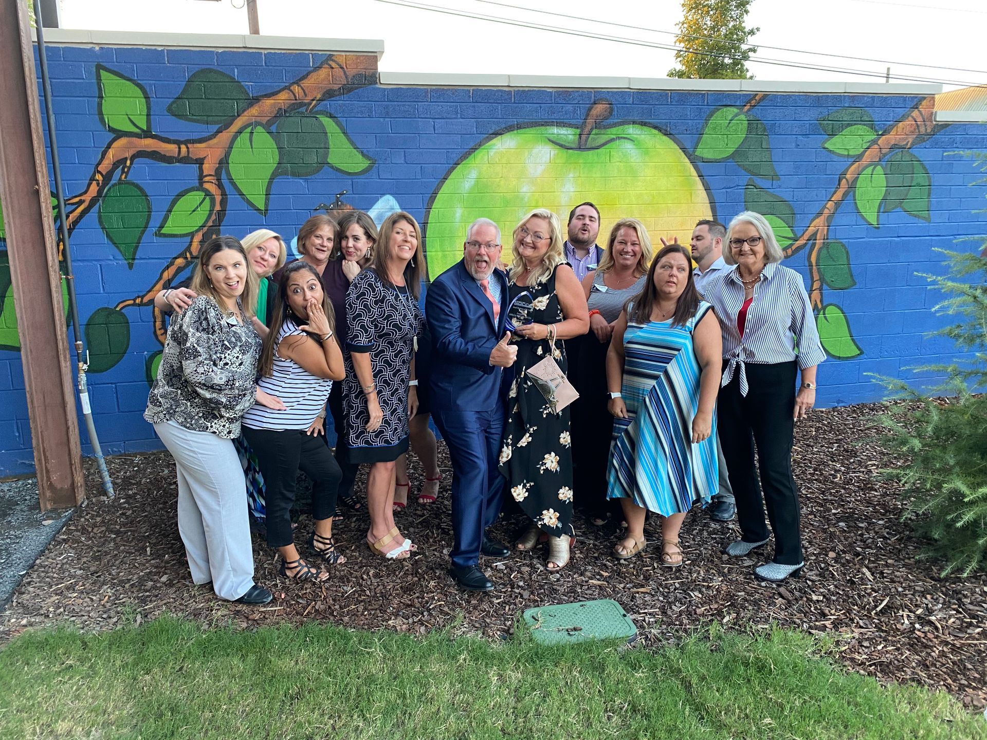 Ashley Lay Real Estate full team photo in front of a colorful mural