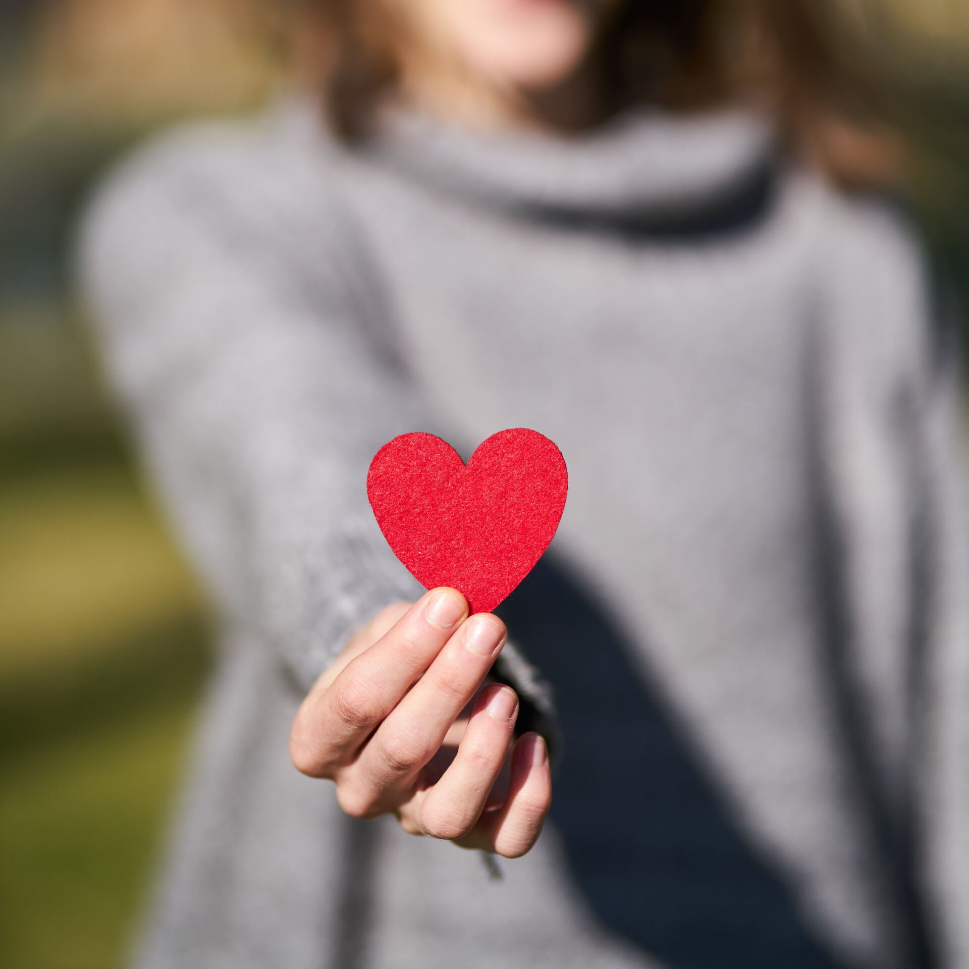 Person holding a red heart, representing Ashley Lay Real Estate's community values