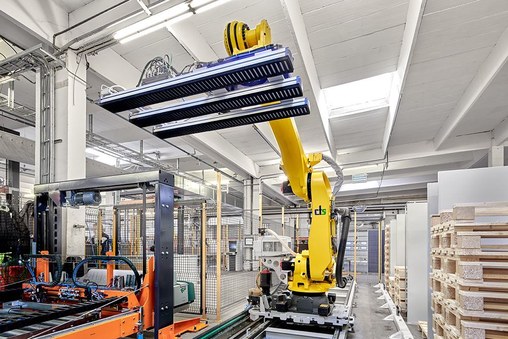 Ein gelber Roboter bewegt eine Palette in einer Fabrik.