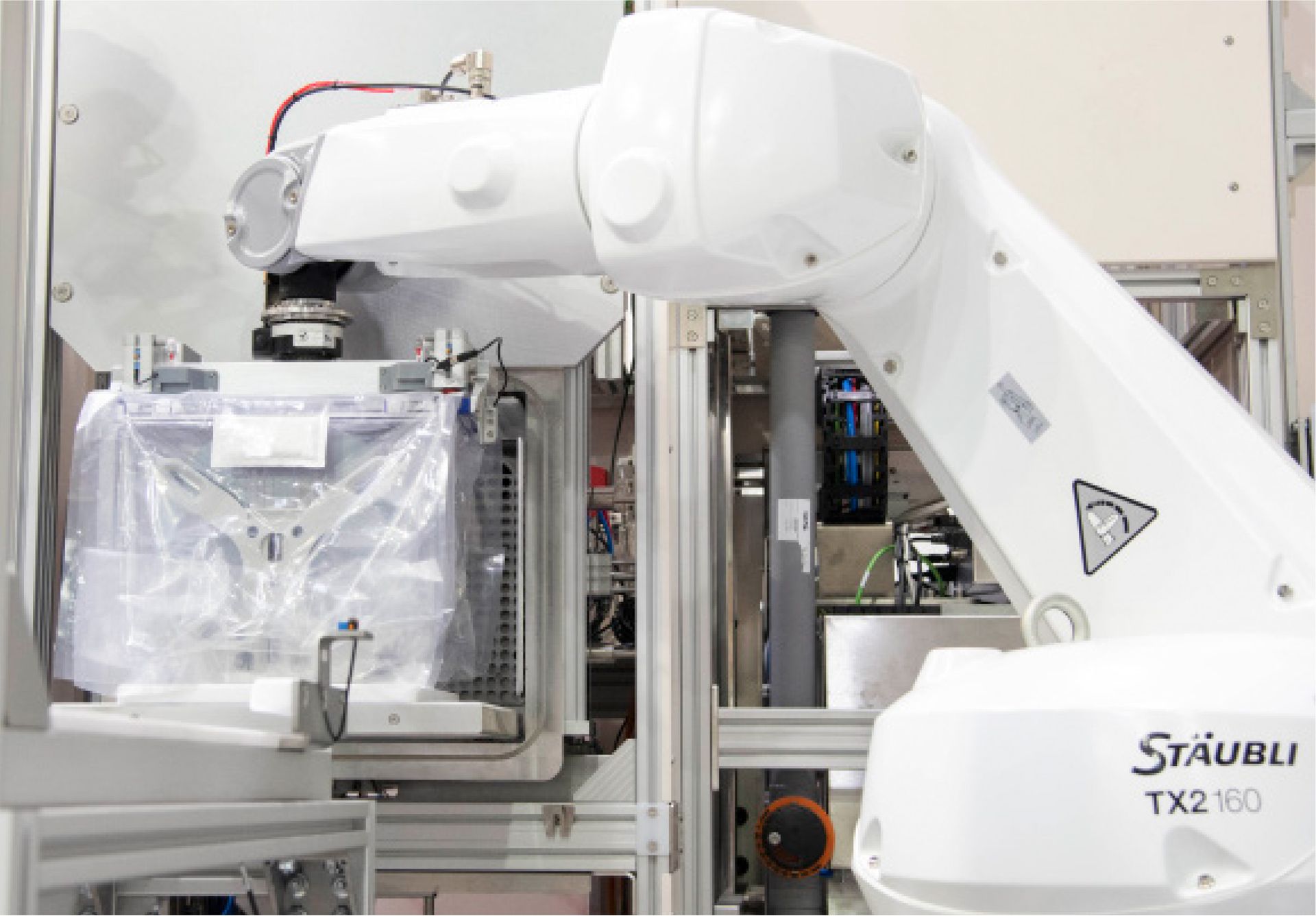 A white robotic arm is working on a machine in a factory.
