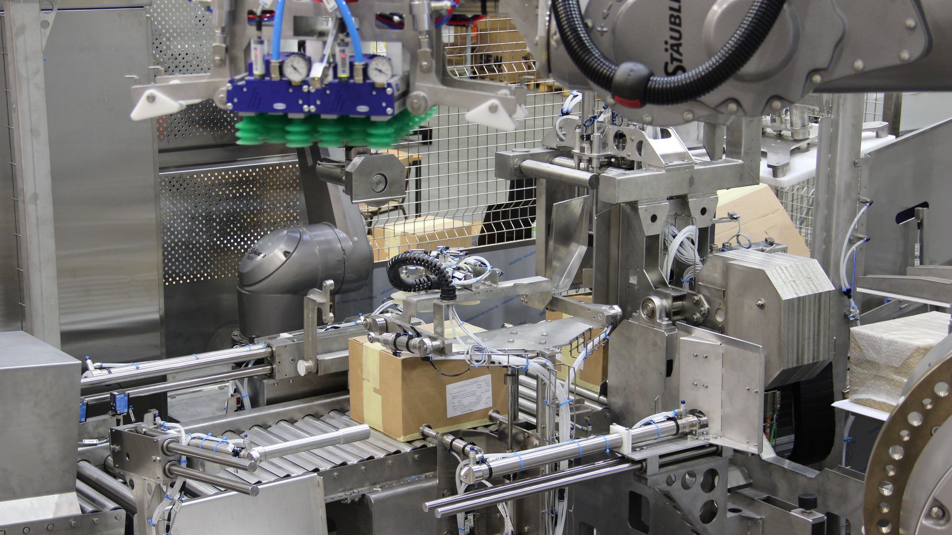 Ein Roboter bewegt eine Kiste auf einem Förderband in einer Fabrik.