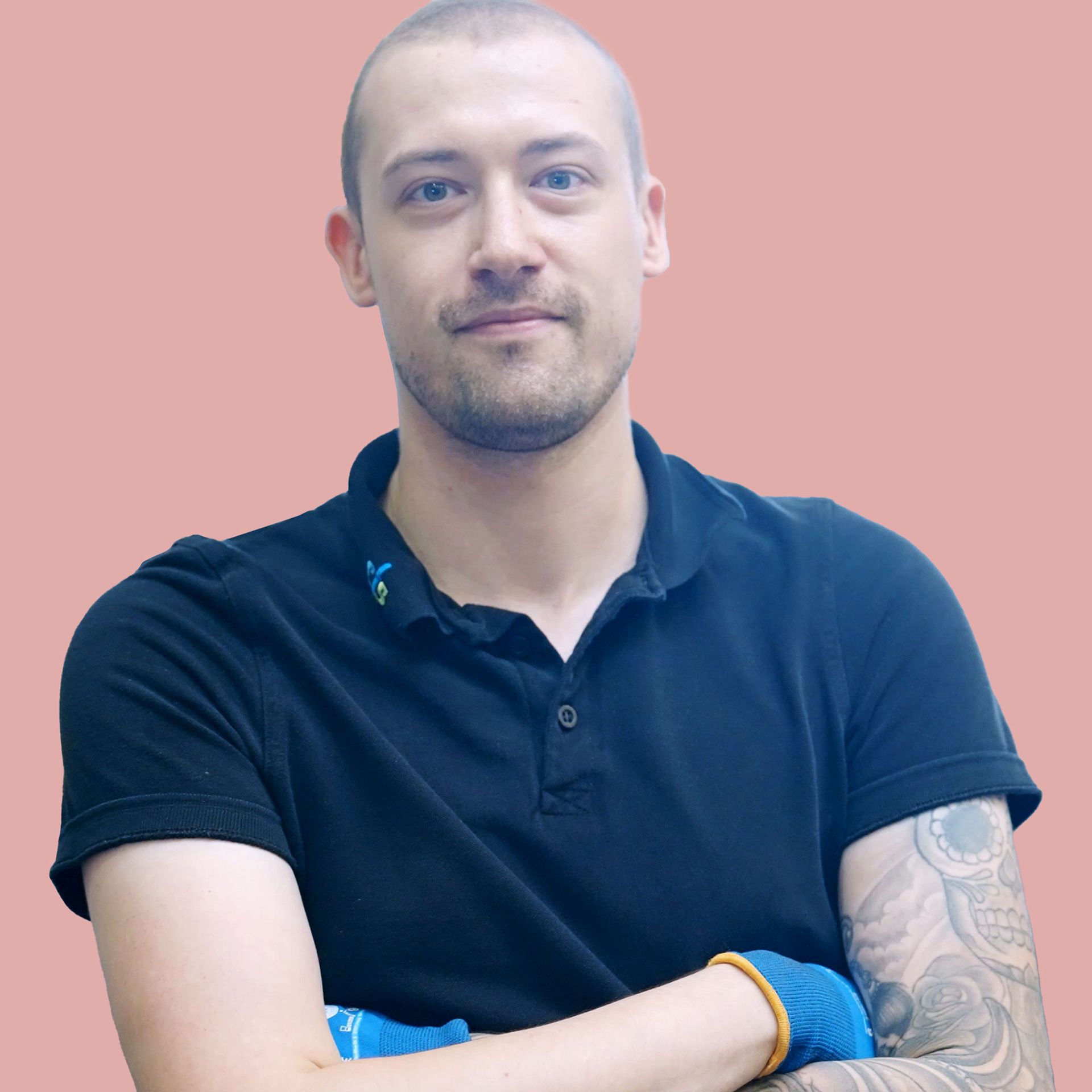 Ein Mann mit einer Tätowierung auf dem Arm trägt ein blaues Poloshirt