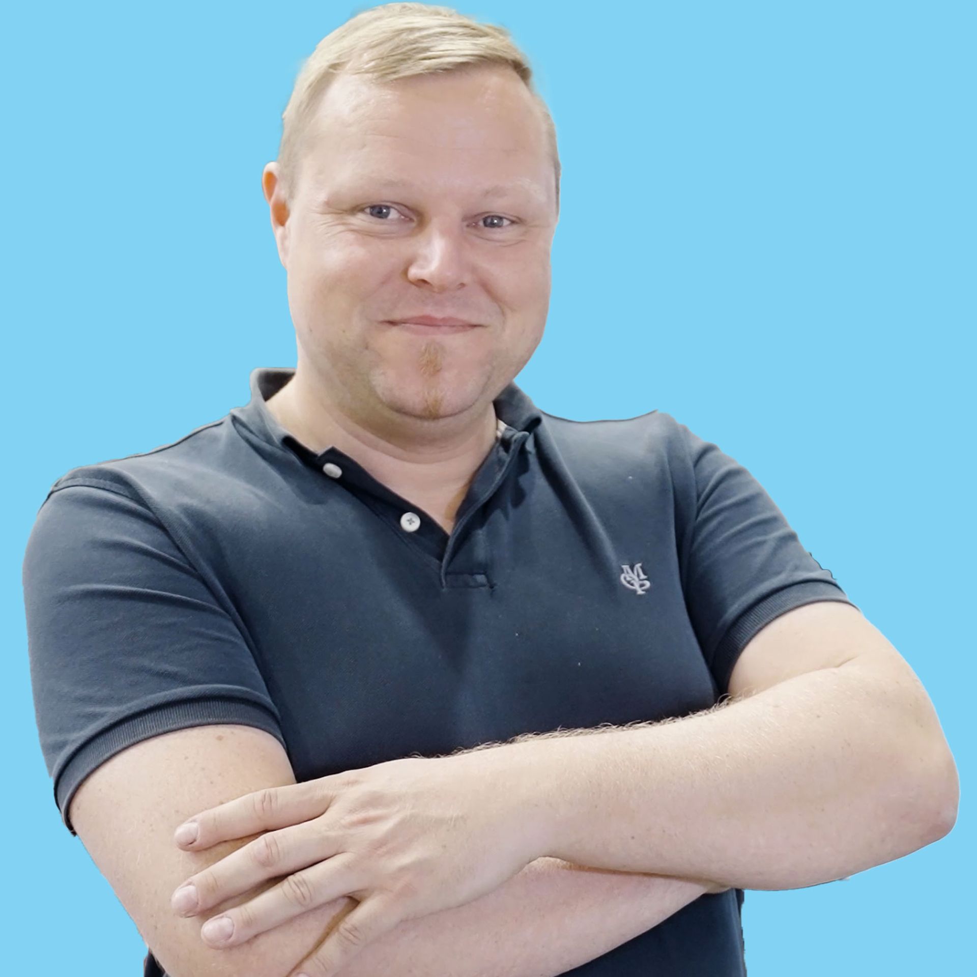Ein Mann in einem blauem Poloshirt mit verschränkten Armen