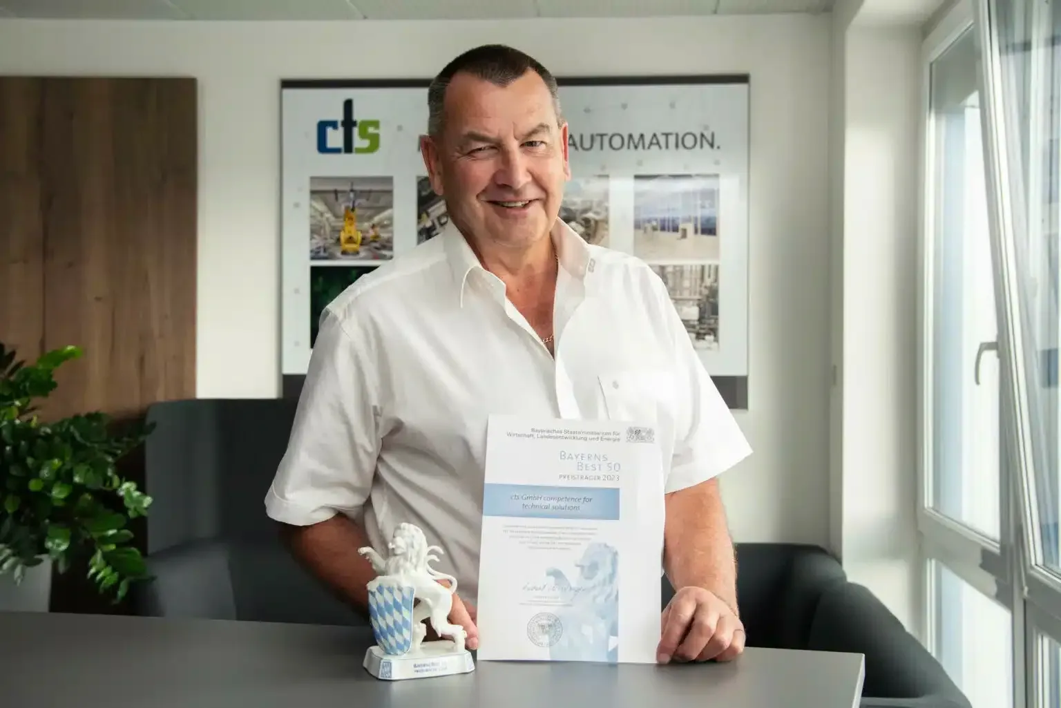 A man in a white shirt is sitting at a table holding a certificate.