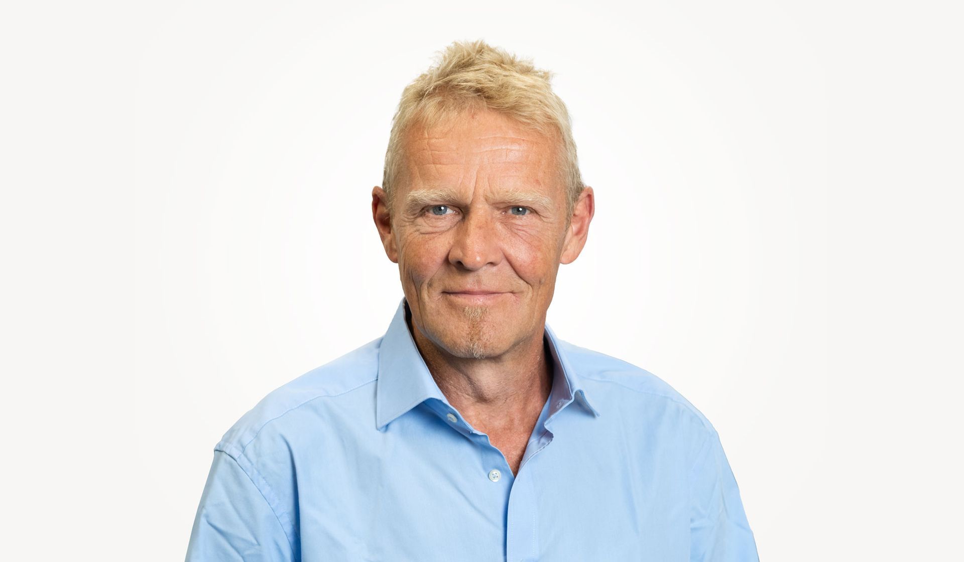 Ein Mann in einem blauen Hemd lächelt in die Kamera.