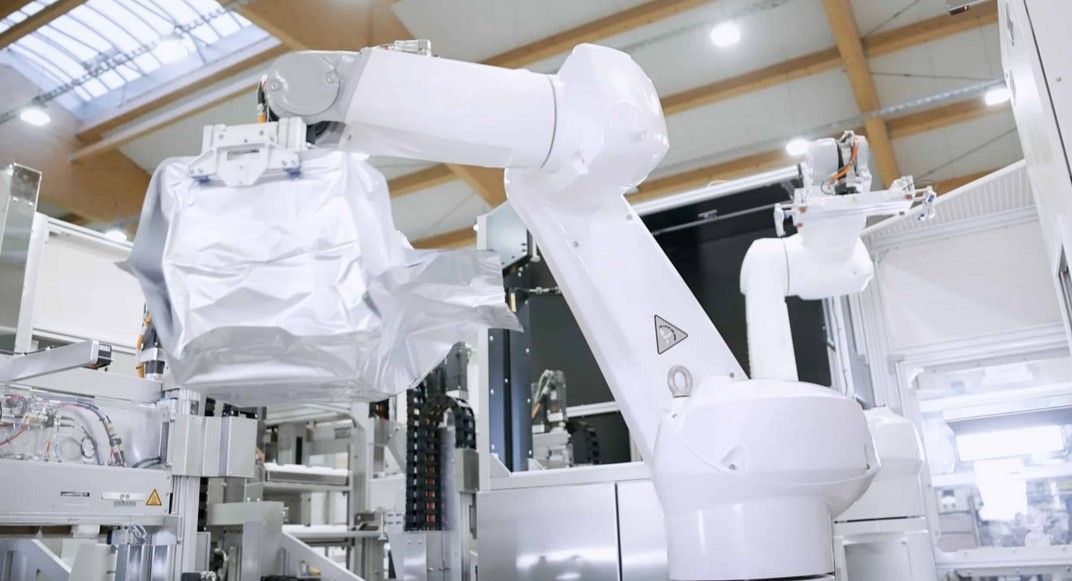 Ein Roboterarm arbeitet an einer Maschine in einer Fabrik.