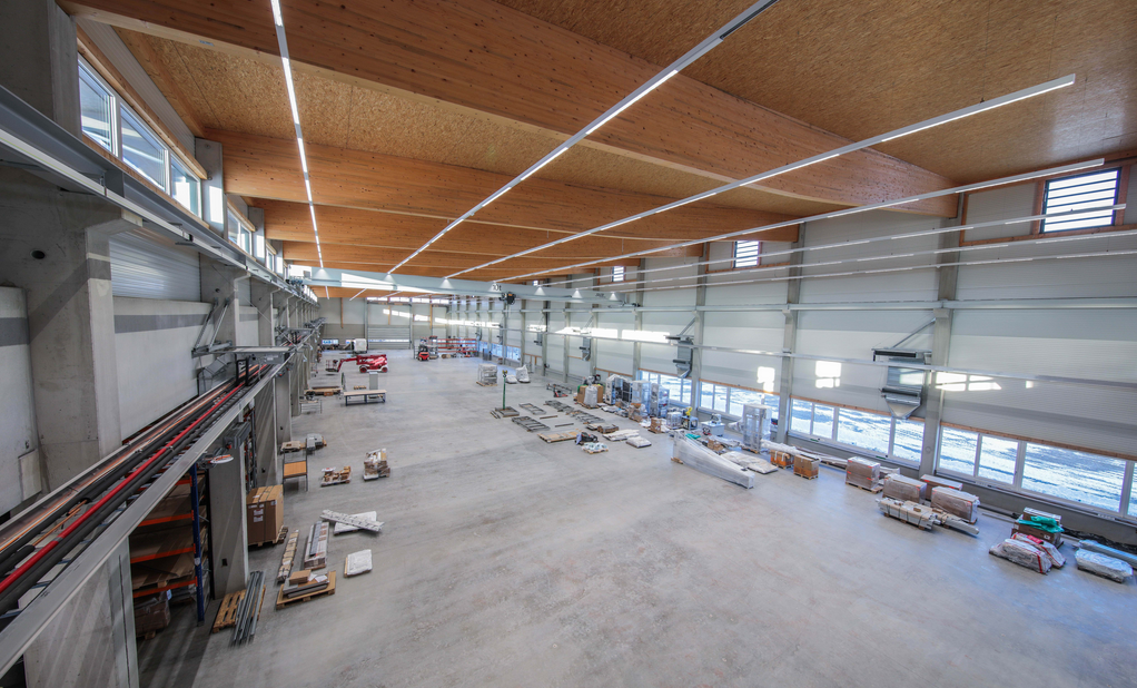 Eine große Fertigungshalle mit Holzdecke und vielen Fenstern
